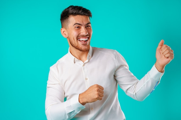 Portrait of excited, successful man raising hands up