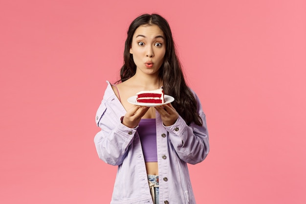Portrait of excited and surprised cute asian girlfriend holding piece of cake