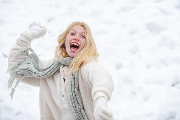 冬の元気な女の子の興奮した女性の肖像画屋外で雪だるま式に遊ぶ幸せな若い女の子...