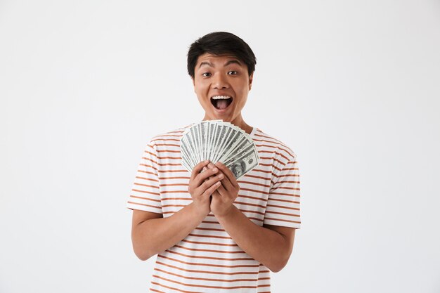 Portrait of an excited young asian man holding money