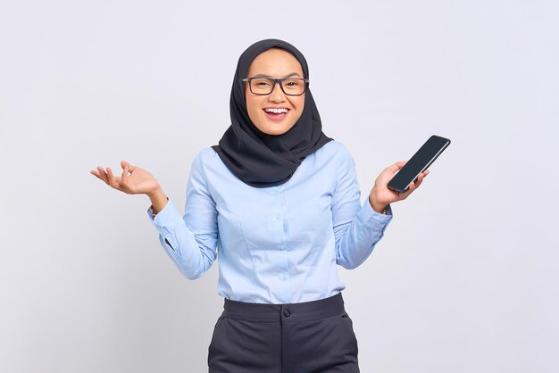 Portrait of excited young Asian woman celebrating with mobile phone isolated on white background