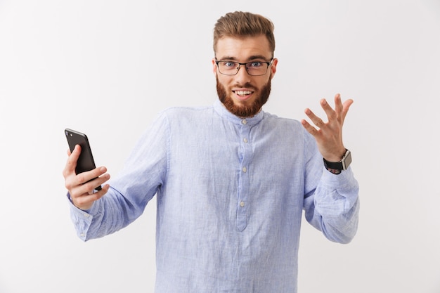 Portrait of an excited young bearded man in eyeglasses