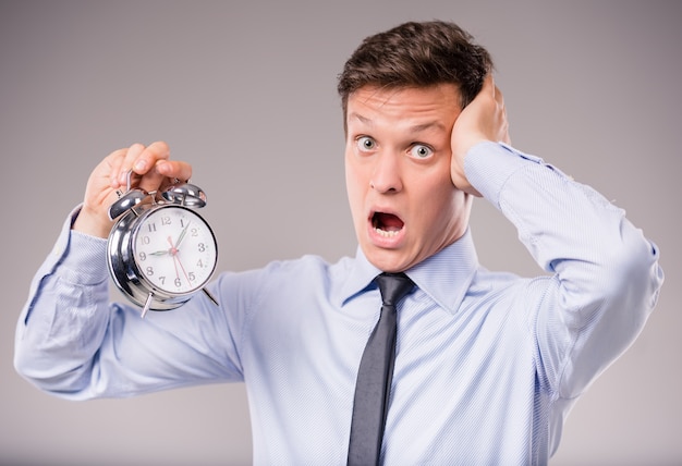 Portrait of excited young businessman holding a clock.