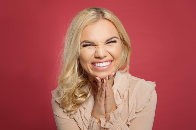 Portrait of excited young casual woman screaming on pink background