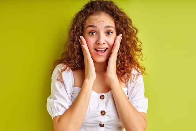 Portrait of excited young girl surprised by something, isolated on green space