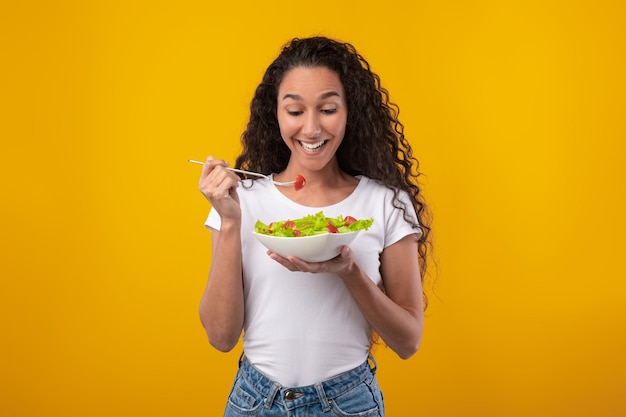 Portrait of excited young lady holding plate with salad