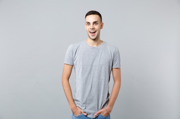 Portrait of excited young man in casual clothes keeping mouth open, holding hands in pockets 