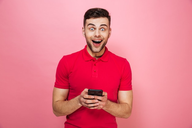 Portrait of an excited young man holding mobile phone