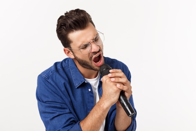 Foto ritratto di un giovane eccitato in maglietta isolato su backgound grigio, cantando.