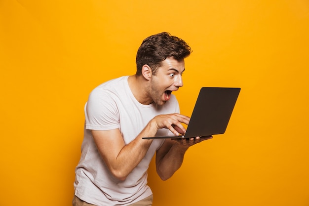 Portrait of an excited young man using laptop