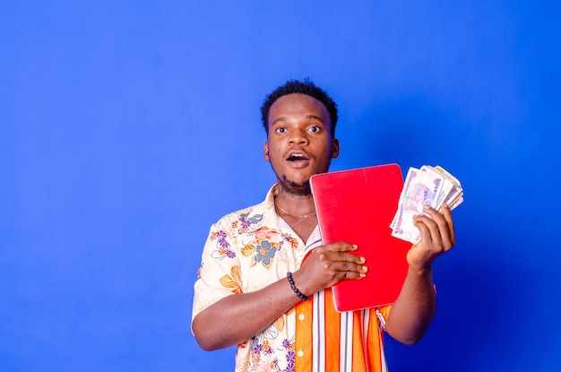 Portrait of excited young modern businessman standing holding laptop