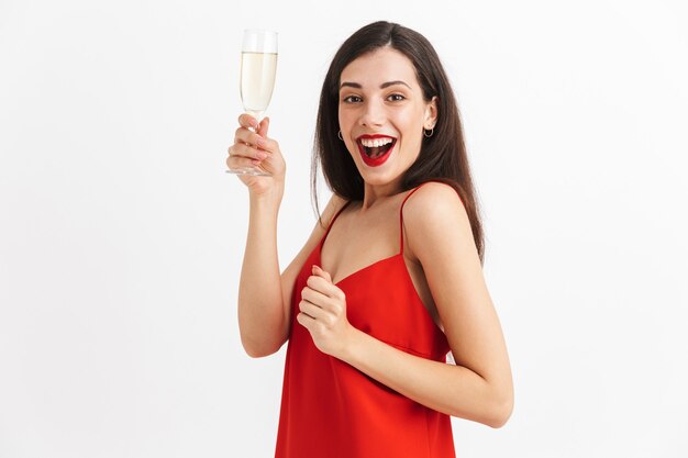 Портрет возбужденной молодой женщины в платье с бокалом шампанского изолированы