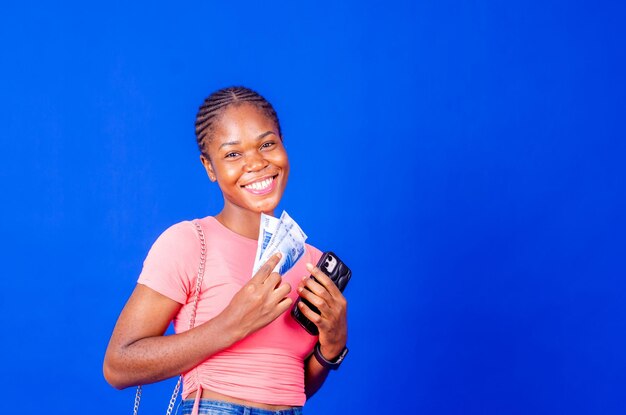 Portrait of an excited young woman holding bunch of money banknotes
