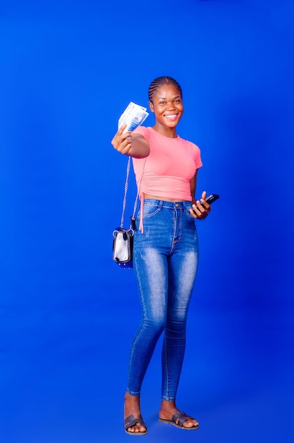 Portrait of an excited young woman holding bunch of money banknotes