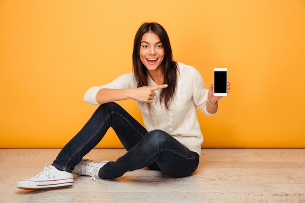 Portrait of an excited young woman sitting on a floor