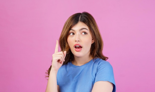 Portrait of excited young woman wearing casual tshirt thinking and imagination isolated over pink background