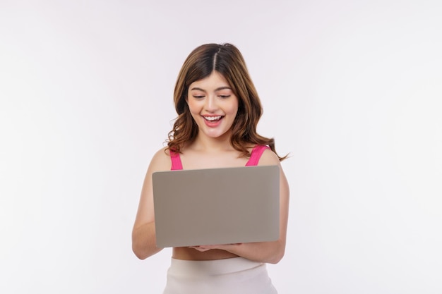 Portrait of excited young woman working on laptop computer isolated over white background