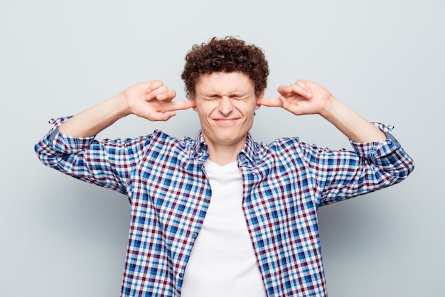 Portrait of exhausted guy doesn't want to listen noise isolated on gray