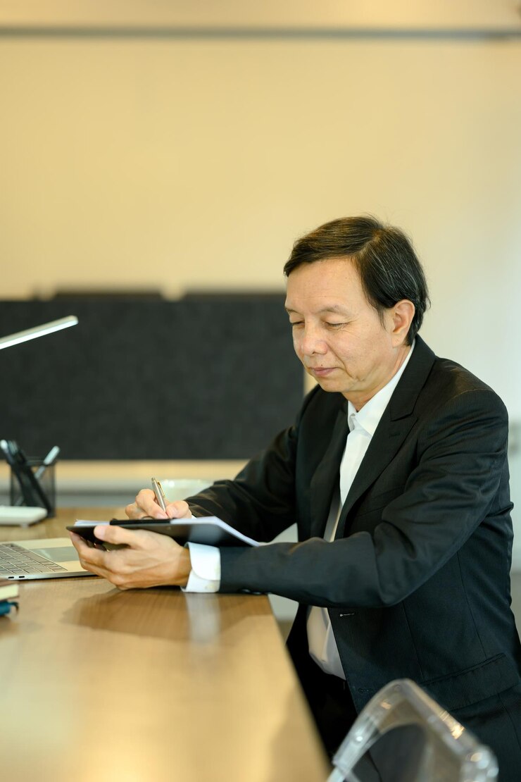 Photo 經驗豐富的中年男性經理在現代工作環境中審查文件的肖像