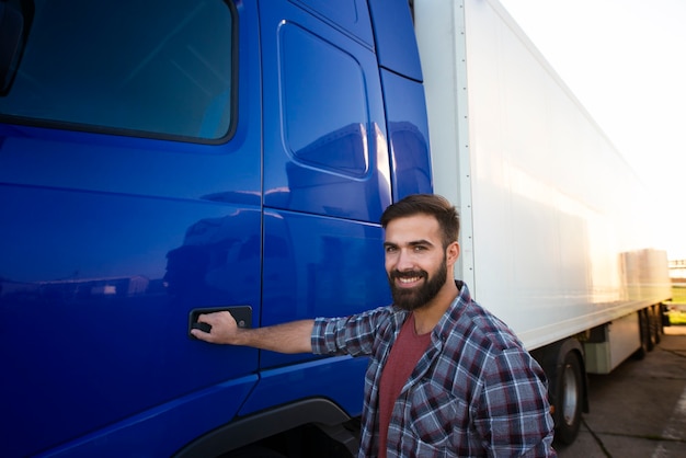 Foto ritratto di autista di camion con esperienza in piedi dal suo veicolo lungo semi camion.