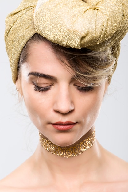 Photo portrait of expressive woman with golden turban on white background