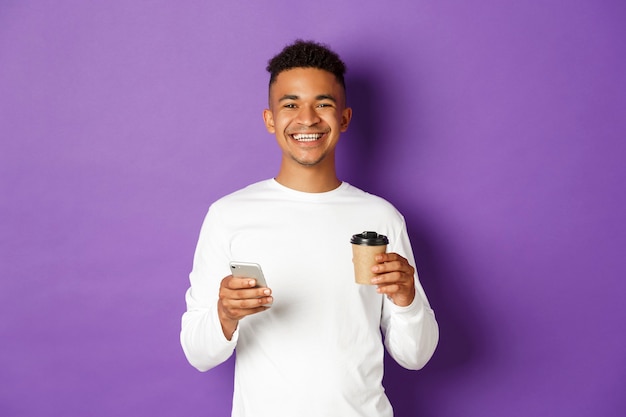 Portrait expressive young man holding cup of coffee and mobile