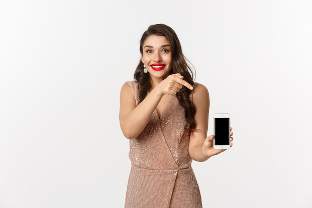 Портрет выразительной молодой женщины в элегантном платье, держащей телефон