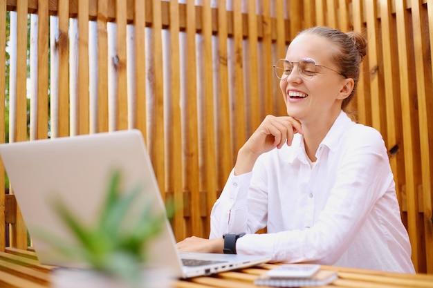 Ritratto di donna estremamente felice che utilizza il computer portatile che lavora su notebook apprendimento a distanza istruzione online e lavoro femminile che ha conversazione online su videochiamata ridendo felicemente