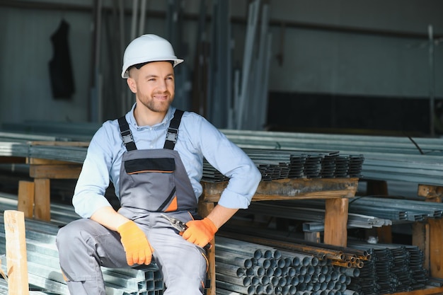 Портрет фабричного рабочего в защитной форме и каске, стоящего у промышленной машины на производственной линии Люди, работающие в промышленности