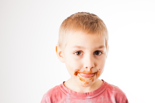 Portrait of fair-haired boy with chocolate on his face isolated on white. Boy after tasting chocolate