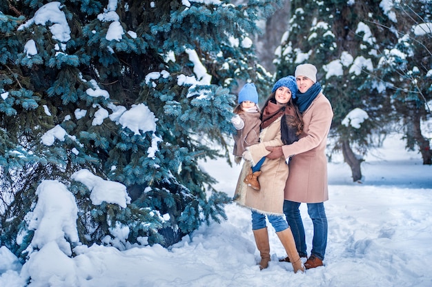 Foto ritratto di una famiglia sullo sfondo di alberi coperti di neve