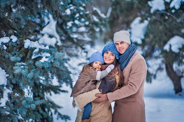 Foto ritratto di una famiglia sullo sfondo di alberi coperti di neve