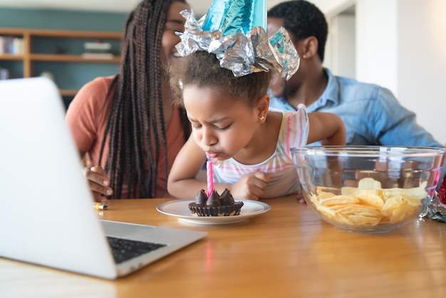 Ritratto di una famiglia che festeggia il compleanno online su una videochiamata mentre si è a casa.