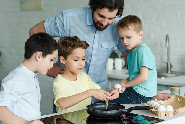 portrait of family cooking eggs for breakfast together in kitchen at home