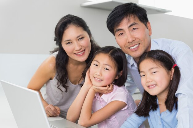 Portrait of a family of four with laptop in kitchen