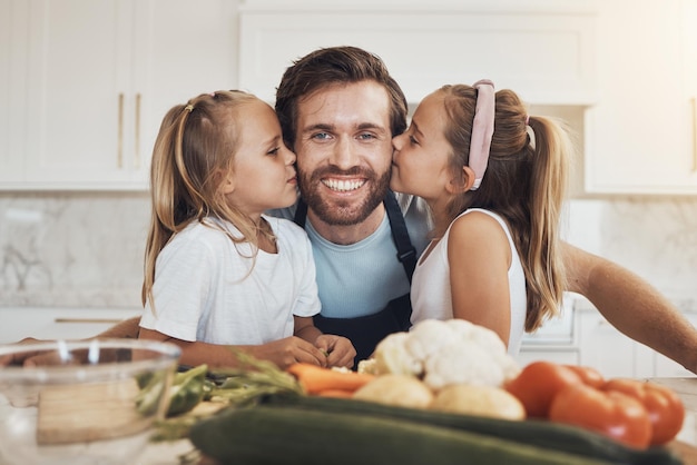 家族の肖像画と ⁇ にキスをする 女の子の子供たちと父親が 家のキッチンで一緒に料理する 顔の笑顔と姉妹が 幸せな親と家で食事を作る