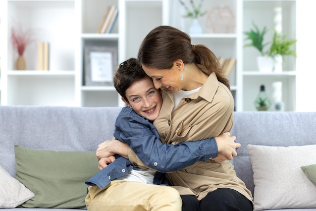 Portrait of a family mother and teenage son sitting at home on the couch and hugging having fun