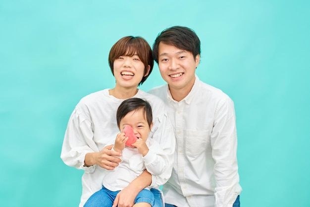 Portrait of a family of three in front of a blue background