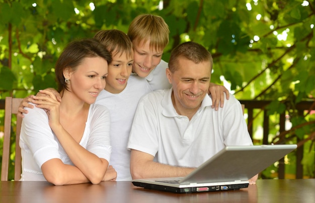 Foto ritratto di una famiglia che utilizza il laptop insieme all'aperto