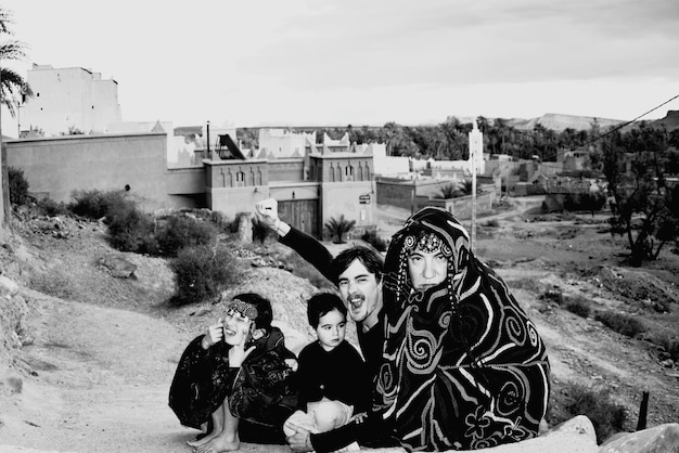 Foto ritratto di una famiglia che indossa abiti tradizionali mentre è seduta all'aperto