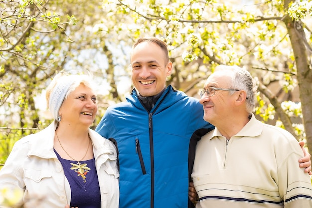 Ritratto di famiglia con figlio adulto all'aperto.