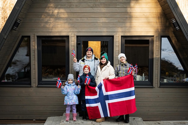 ノルウェーの旗スカンジナビアの文化ノルウェーの人々 を保持している小屋の家の外の子供たちと家族の肖像画