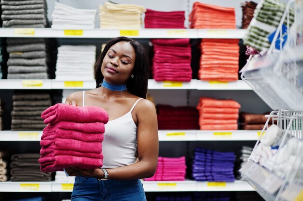 Портрет фантастической Афро-американской женщины держа розовые полотенца в ее руках в магазине.