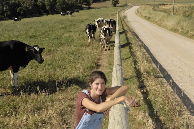 Portrait of a farmer with her cows in the field