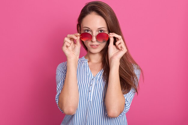 Portrait of fashion attractive woman peeking over sunglasses.