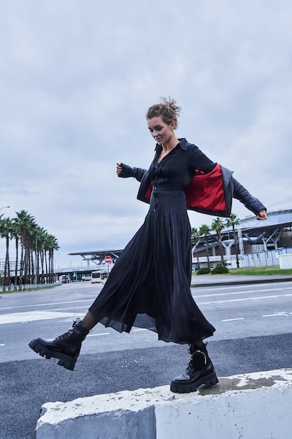 Portrait of fashion model girl in black clothes crosses the city road