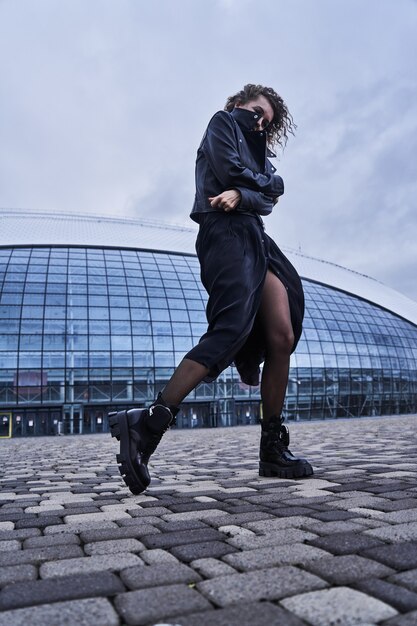 Портрет девушки фотомодели в черной одежде позирует на фоне города