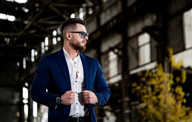 Portrait of fashion model man in modern sunglasses and suit Waist portrait of a man in formal clothes Closeup