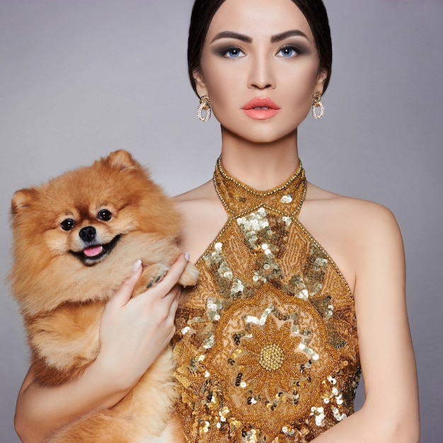 Portrait of a fashion model with a small dog in his hands