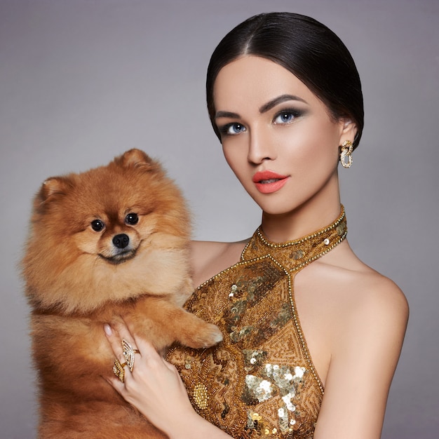 Portrait of a fashion model with a small dog in his hands